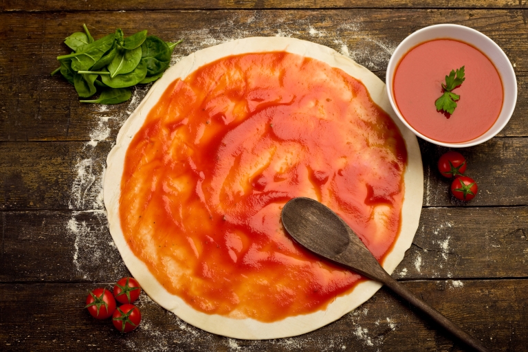 pizza dough with tomato sauce on rustical wooden table